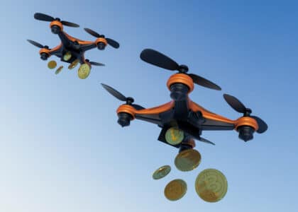 Deux drones en vol larguant des tokens de Bitcoin, illustrant la distribution de cryptomonnaies à travers le concept d’airdrop.