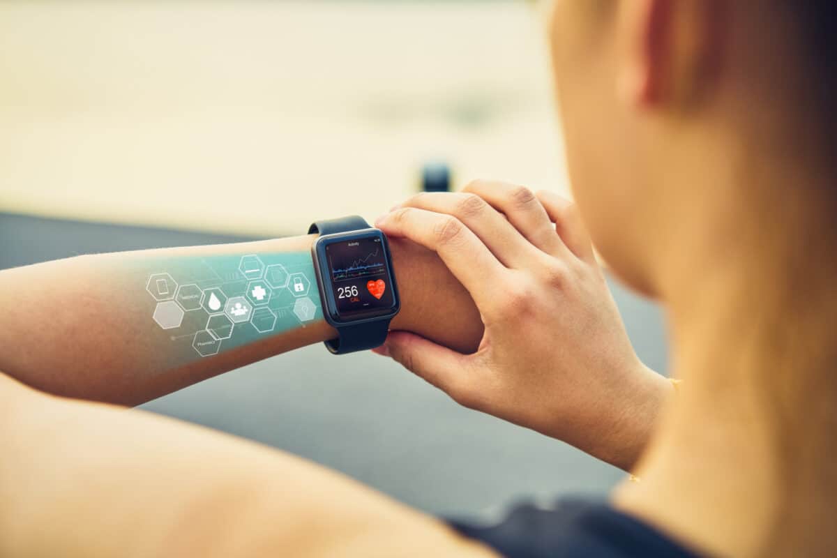Personne utilisant une montre connectée affichant des données de santé et des symboles numériques projetés sur le bras
