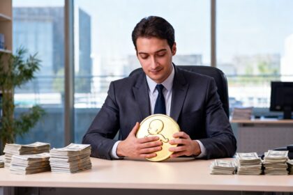 Un cadre en costume serre contre lui une grande pièce dorée à son bureau, des liasses de billets posées de côté.