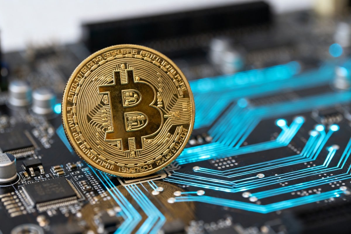 Une pièce dorée au symbole du bitcoin posée sur une carte électronique aux circuits bleus lumineux.