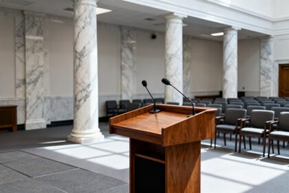 Salle de conférence institutionnelle vide avec pupitres et micros