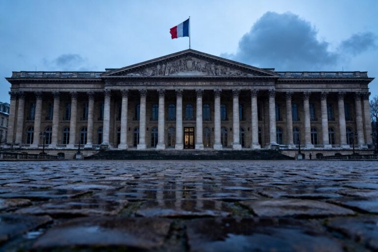 Façade néoclassique du Sénat français surmontée du drapeau tricolore sous un ciel d'hiver