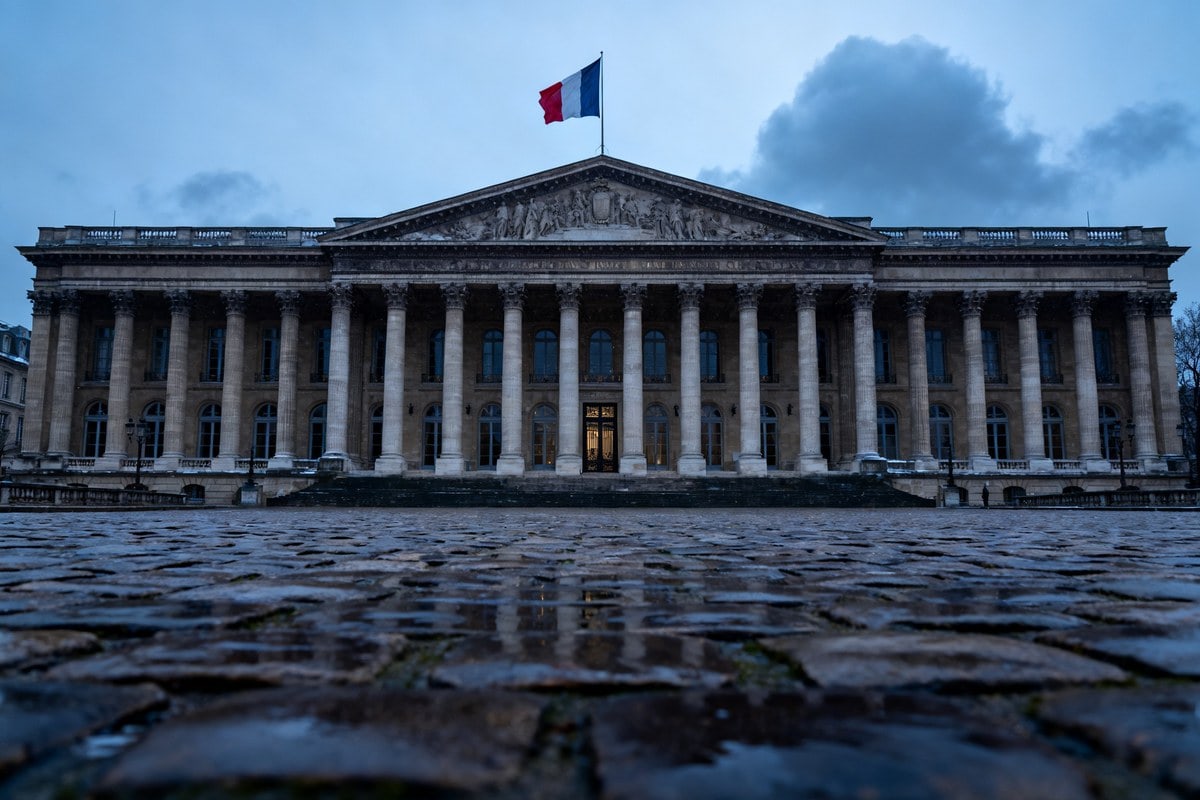 Façade néoclassique du Sénat français surmontée du drapeau tricolore sous un ciel d'hiver