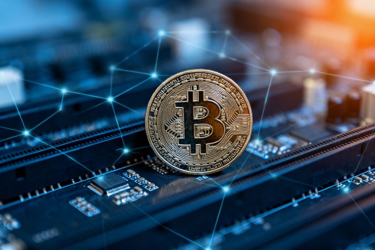 Pièce de bitcoin dressée sur une carte électronique parcourue de lignes lumineuses bleues en réseau